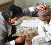 Doctor checking eyes of old man
